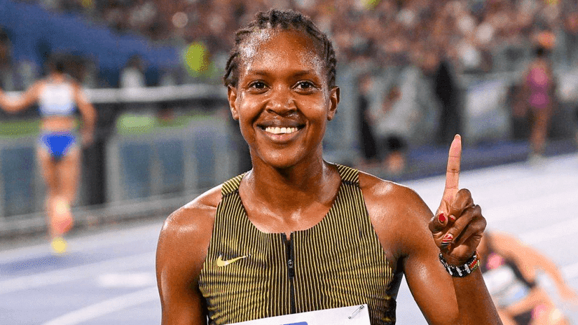 Faith Kipyegon smiling and holding her finger up after a race, symbolising her ambition to break the 4-minute mile barrier.