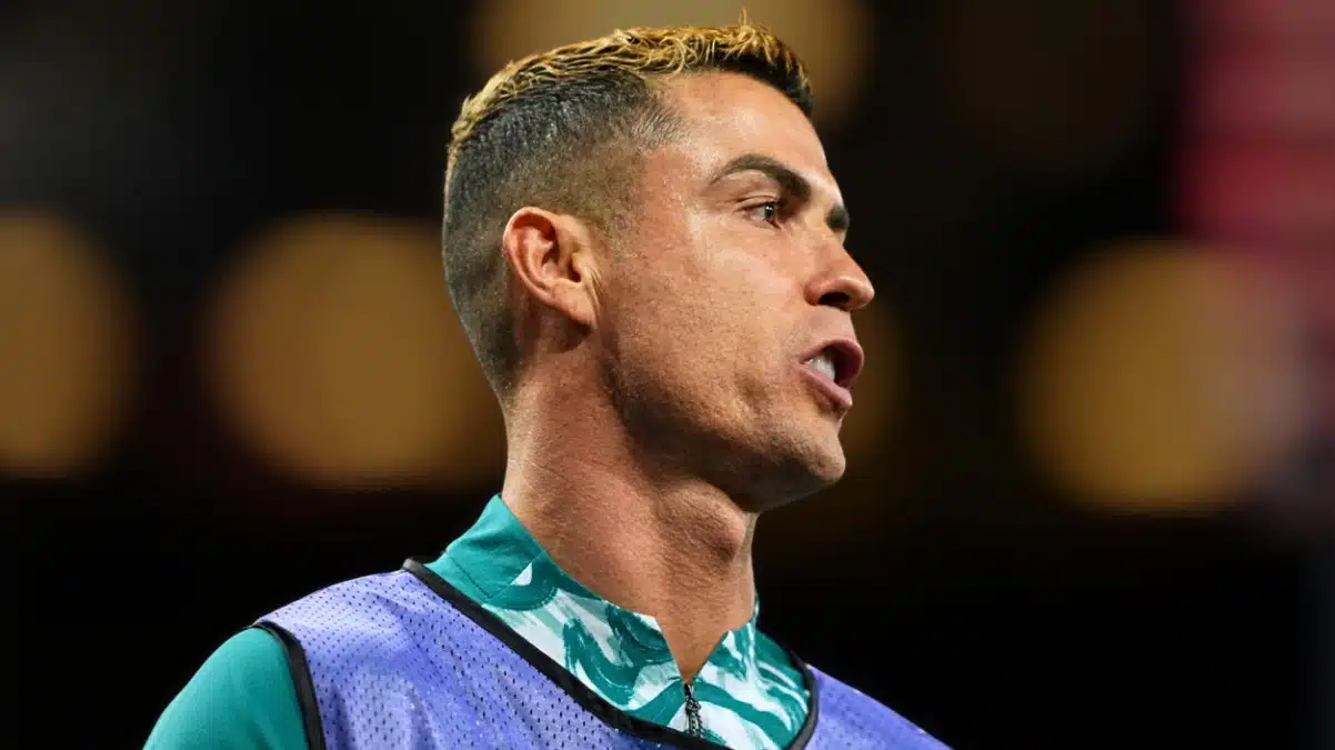 Cristiano Ronaldo in a training bib, profile view mid-shout.