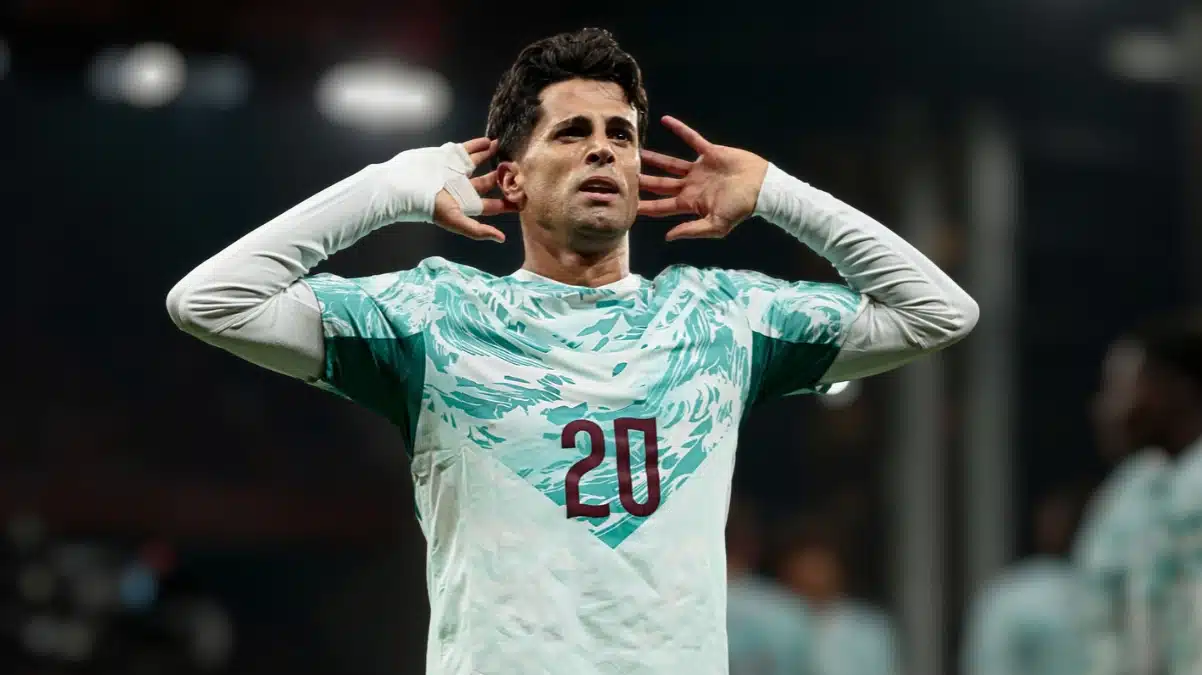 João Cancelo cupping both ears in celebration wearing number 20.