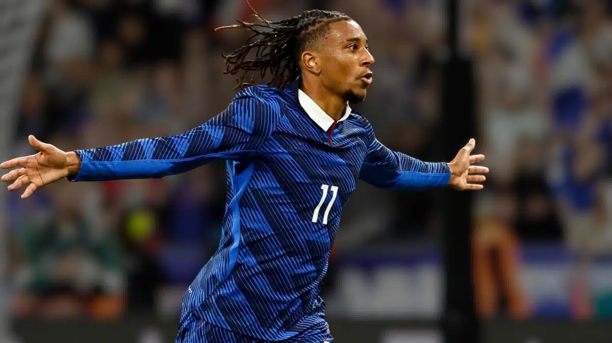 Michael Olise celebrating with arms outstretched in France's blue number 11 kit.