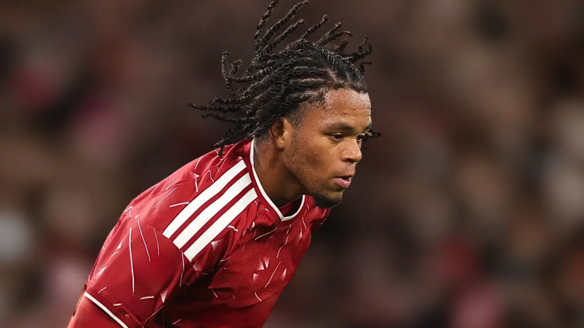 Rio Ngumoha leaning forward in a red kit with white stripes.